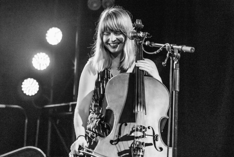 Cellist & singer songwriter Monique Clare on stage with her cello, smiling.
